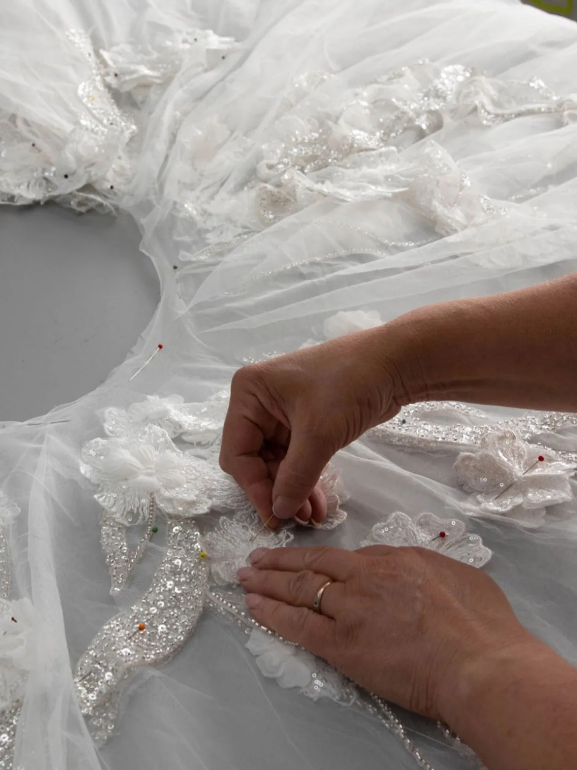 Sartoria interna Idea Sposa: applicazioni in pizzo cucite a mano su un abito da sposa